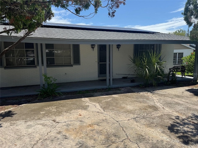 11423 77th Ave, Seminole, FL 33772 - view of front of house with brick siding, solar panels, and a shingled roof