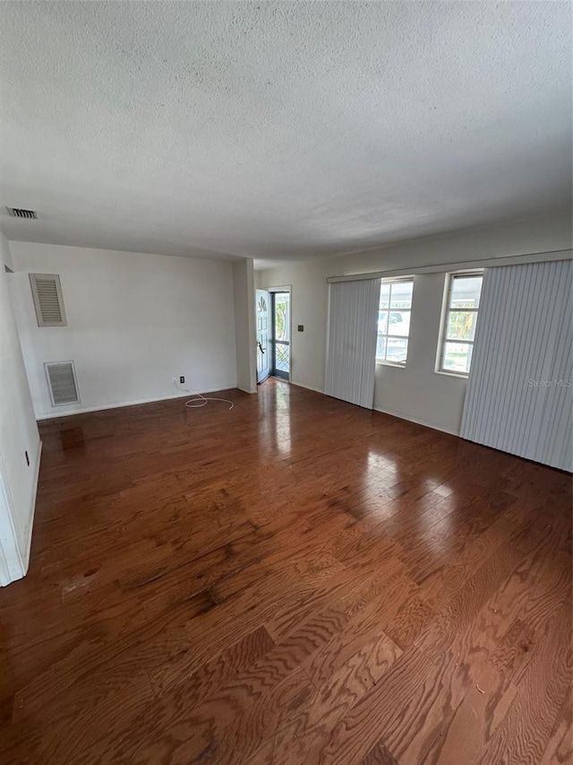 11423 77th Ave, Seminole, FL 33772 - unfurnished living room featuring a textured ceiling and wood finished floors
