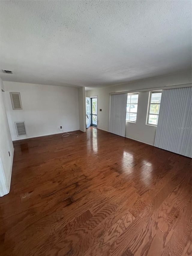 11423 77th Ave, Seminole, FL 33772 - unfurnished living room with a textured ceiling and wood finished floors