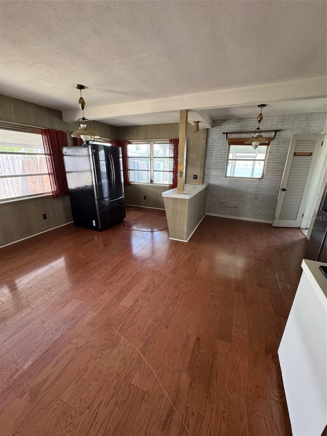 11423 77th Ave, Seminole, FL 33772 - unfurnished dining area featuring a textured ceiling, dark wood-type flooring, and brick wall