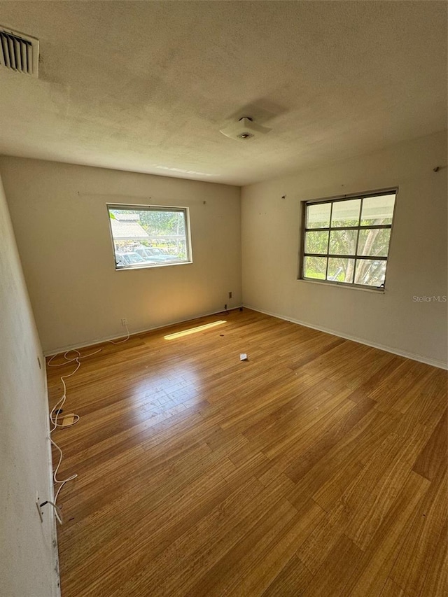 11423 77th Ave, Seminole, FL 33772 - empty room with plenty of natural light, wood finished floors, and a textured ceiling