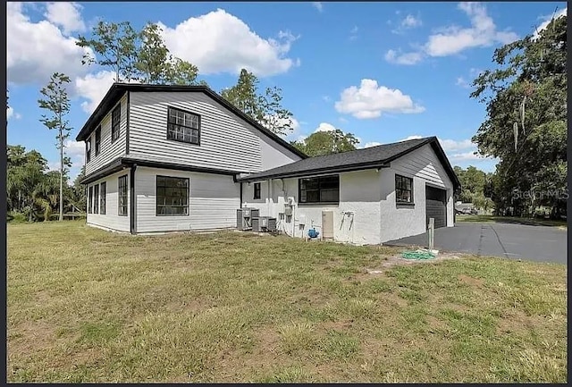 19003 Cedar Ln, Lutz, FL 33548 - rear view of house featuring asphalt driveway, a garage, and a lawn