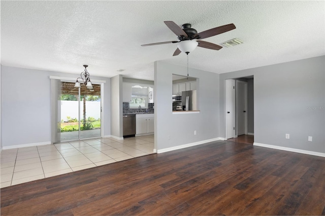 1806 11th St SW, Largo, FL 33778 - unfurnished living room with a textured ceiling, a ceiling fan, light wood-type flooring, and a chandelier