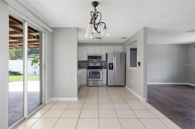 1806 11th St SW, Largo, FL 33778 - kitchen featuring stainless steel appliances, decorative backsplash, a chandelier, a textured ceiling, and decorative light fixtures