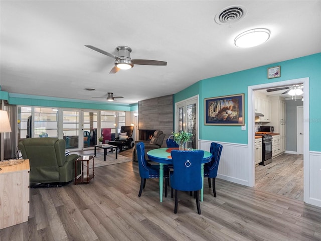 3944 49th Ave S, Saint Petersburg, FL 33711 - dining room with ceiling fan, light wood-type flooring, a wainscoted wall, and a large fireplace