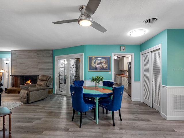 3944 49th Ave S, Saint Petersburg, FL 33711 - dining area featuring ceiling fan, wainscoting, a tiled fireplace, and wood finished floors