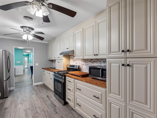 3944 49th Ave S, Saint Petersburg, FL 33711 - kitchen featuring wood counters, appliances with stainless steel finishes, a ceiling fan, under cabinet range hood, and backsplash