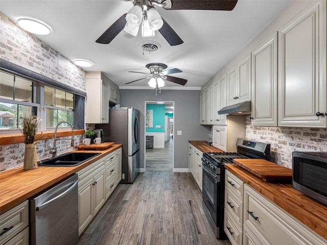 3944 49th Ave S, Saint Petersburg, FL 33711 - kitchen with butcher block countertops, appliances with stainless steel finishes, under cabinet range hood, ceiling fan, and decorative backsplash