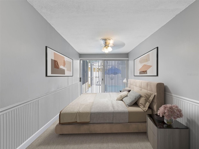 3944 49th Ave S, Saint Petersburg, FL 33711 - carpeted bedroom with access to exterior, wainscoting, and a textured ceiling