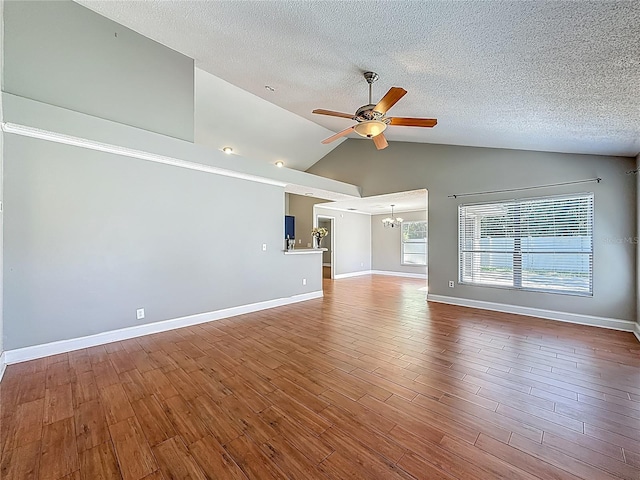 6001 Lemon Tree Ct, Tampa, FL 33625 - unfurnished living room featuring a ceiling fan, a chandelier, a textured ceiling, wood finished floors, and high vaulted ceiling