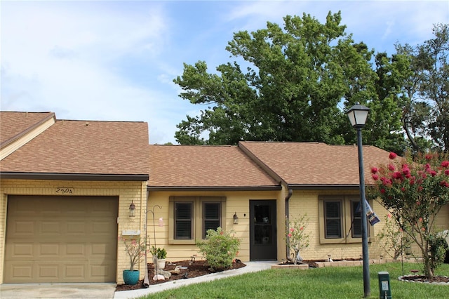 2101 Sunset Point Rd Unit 2304, Clearwater, FL 33765 - view of front of house featuring roof with shingles, an attached garage, brick siding, and a front lawn