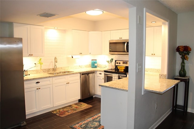 2101 Sunset Point Rd Unit 2304, Clearwater, FL 33765 - kitchen featuring appliances with stainless steel finishes, backsplash, wood finish floors, a peninsula, and white cabinetry