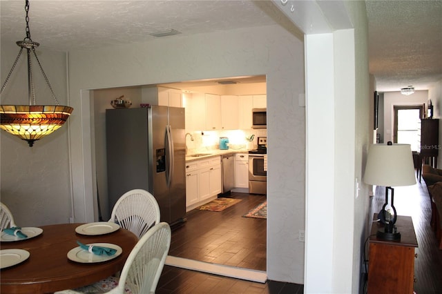 2101 Sunset Point Rd Unit 2304, Clearwater, FL 33765 - dining area with a textured ceiling, a textured wall, and dark wood finished floors