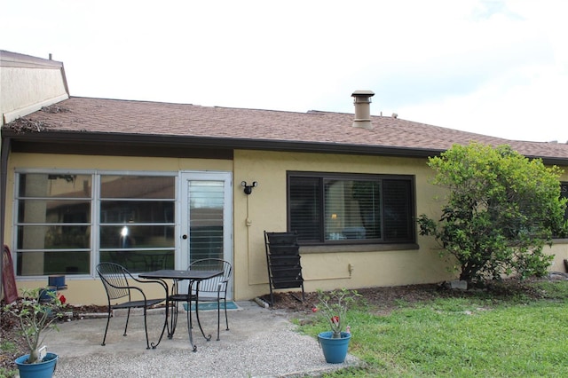2101 Sunset Point Rd Unit 2304, Clearwater, FL 33765 - back of house featuring a patio, stucco siding, roof with shingles, and a yard