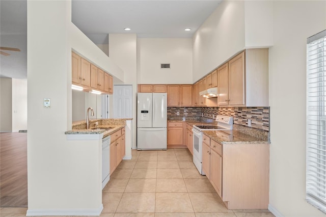 11412 Alden Ct, Hudson, FL 34667 - kitchen with white appliances, under cabinet range hood, a high ceiling, backsplash, and light stone counters