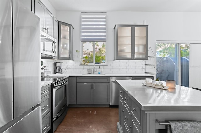 851 3rd Ave N, Saint Petersburg, FL 33701 - kitchen featuring stainless steel appliances, gray cabinets, concrete floors, backsplash, and glass insert cabinets