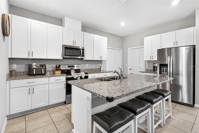 33854 Floating Heart Ct, Wesley Chapel, FL 33545 - kitchen featuring stainless steel appliances, light tile patterned flooring, a breakfast bar, recessed lighting, and dark stone counters