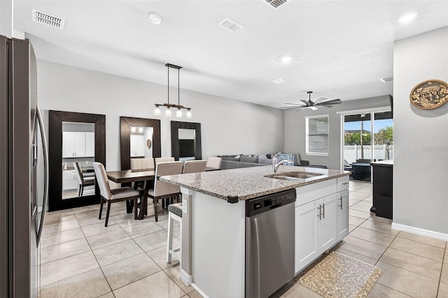 33854 Floating Heart Ct, Wesley Chapel, FL 33545 - kitchen with stainless steel appliances, open floor plan, light tile patterned floors, a kitchen island with sink, and light stone counters