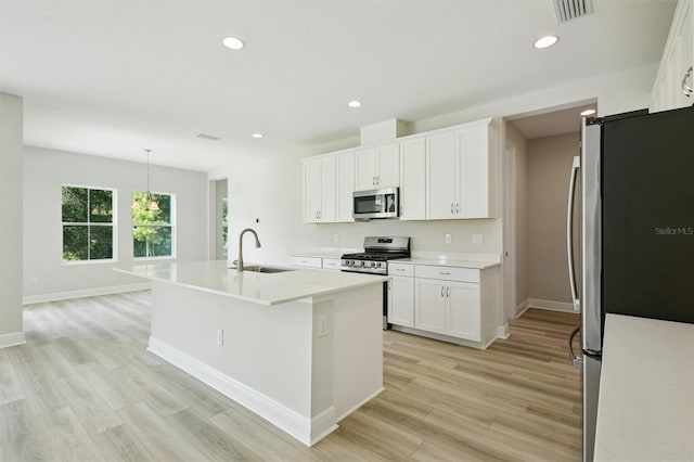 12758 Oak Hill Way, Parrish, FL 34219 - kitchen with appliances with stainless steel finishes, light wood-style flooring, white cabinetry, light countertops, and a center island with sink