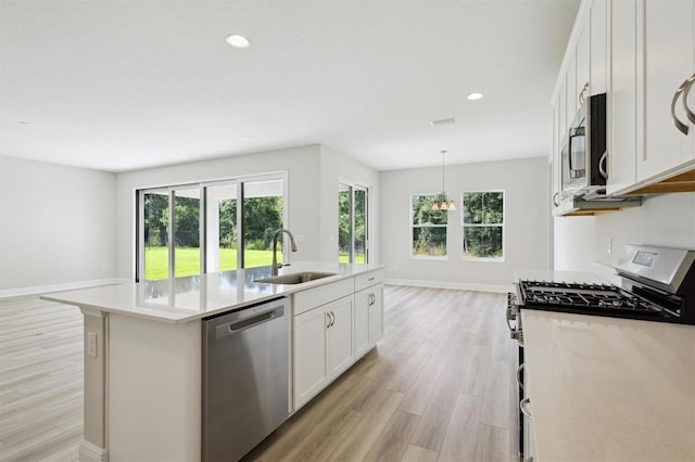 12758 Oak Hill Way, Parrish, FL 34219 - kitchen with stainless steel appliances, light wood finished floors, white cabinets, a center island with sink, and light countertops