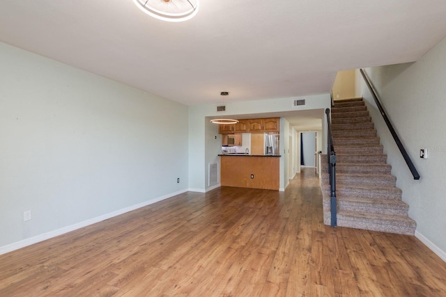 9660 Tara Cay Ct Unit 38, Seminole, FL 33776 - unfurnished living room featuring light wood-type flooring and stairway