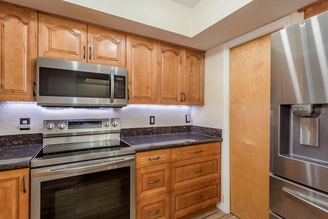 9660 Tara Cay Ct Unit 38, Seminole, FL 33776 - kitchen with stainless steel appliances, dark stone counters, and brown cabinets