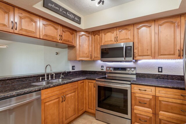 9660 Tara Cay Ct Unit 38, Seminole, FL 33776 - kitchen featuring appliances with stainless steel finishes, dark stone counters, a textured ceiling, light tile patterned flooring, and brown cabinetry