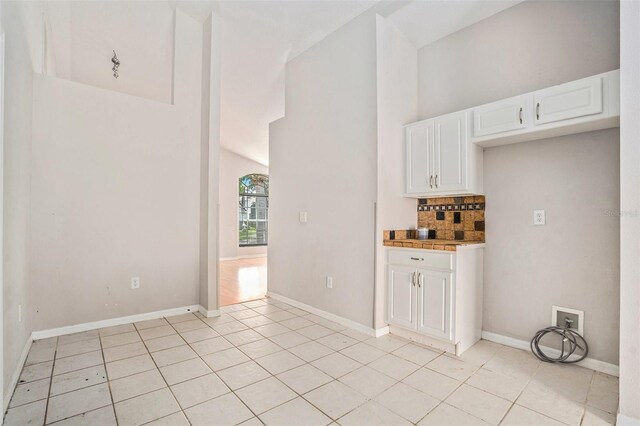 10039 Creek Bluff Dr, Riverview, FL 33578 - kitchen with light tile patterned floors, decorative backsplash, white cabinetry, a high ceiling, and light countertops