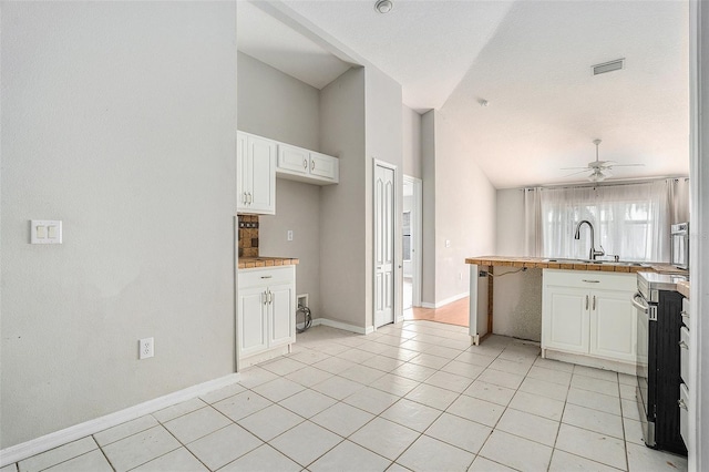 10039 Creek Bluff Dr, Riverview, FL 33578 - kitchen with a peninsula, white cabinetry, light tile patterned floors, and high vaulted ceiling