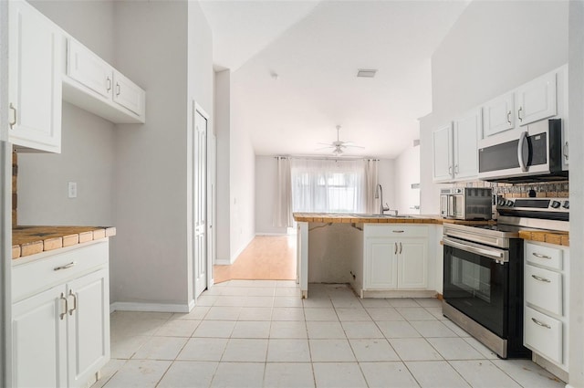 10039 Creek Bluff Dr, Riverview, FL 33578 - kitchen featuring stainless steel appliances, a peninsula, white cabinets, and a ceiling fan