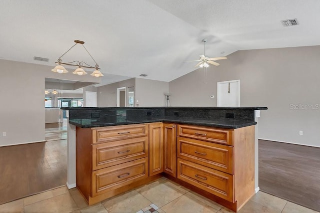 3902 Shoreside Cir, Tampa, FL 33624 - kitchen featuring a ceiling fan, vaulted ceiling, brown cabinets, pendant lighting, and dark stone counters