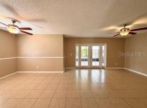 5110 Corvette Dr, Tampa, FL 33624 - empty room with a ceiling fan, a textured ceiling, light tile patterned flooring, and french doors