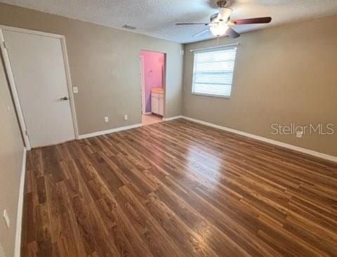 5110 Corvette Dr, Tampa, FL 33624 - unfurnished bedroom with wood finished floors, a textured ceiling, connected bathroom, and a ceiling fan
