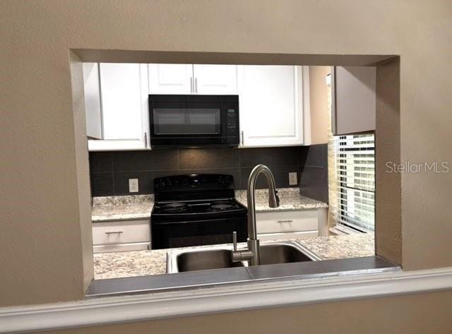 5110 Corvette Dr, Tampa, FL 33624 - kitchen with black appliances, decorative backsplash, white cabinetry, and light stone counters