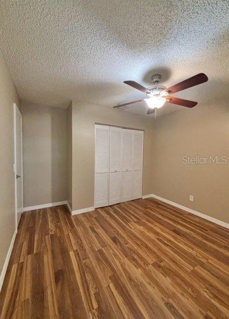 5110 Corvette Dr, Tampa, FL 33624 - unfurnished bedroom with wood finished floors, a closet, a textured ceiling, and ceiling fan
