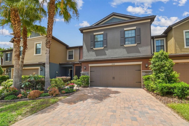28568 Tranquil Lake Cir, Wesley Chapel, FL 33543 - view of front facade with stucco siding, an attached garage, decorative driveway, and stone siding