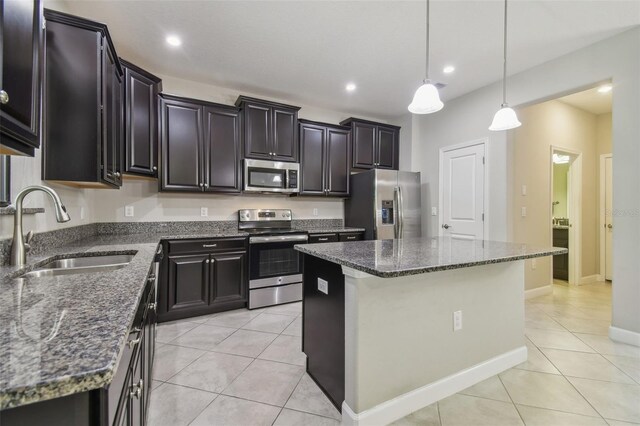 28568 Tranquil Lake Cir, Wesley Chapel, FL 33543 - kitchen featuring appliances with stainless steel finishes, light tile patterned floors, a kitchen island, dark stone counters, and hanging light fixtures