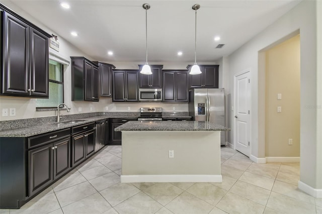 28568 Tranquil Lake Cir, Wesley Chapel, FL 33543 - kitchen featuring appliances with stainless steel finishes, dark stone counters, a kitchen island, hanging light fixtures, and light tile patterned flooring