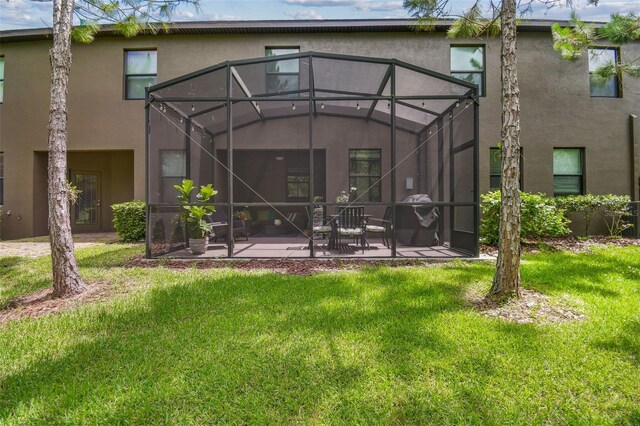 28568 Tranquil Lake Cir, Wesley Chapel, FL 33543 - rear view of property featuring stucco siding, a patio, a yard, and glass enclosure