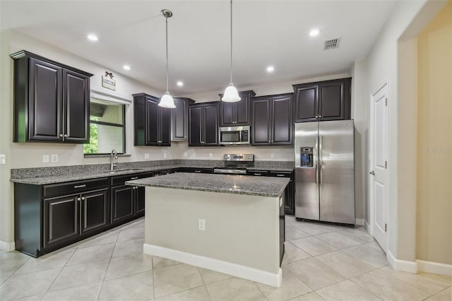 28568 Tranquil Lake Cir, Wesley Chapel, FL 33543 - kitchen featuring appliances with stainless steel finishes, a kitchen island, dark stone countertops, decorative light fixtures, and light tile patterned floors