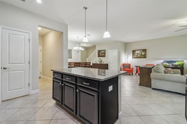 28568 Tranquil Lake Cir, Wesley Chapel, FL 33543 - kitchen with dark cabinetry, open floor plan, light tile patterned floors, stone countertops, and decorative light fixtures