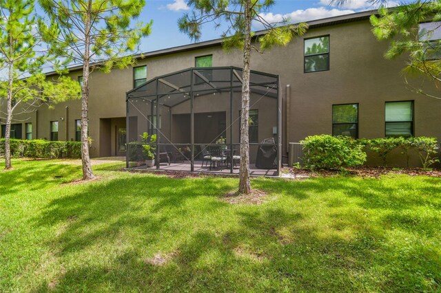 28568 Tranquil Lake Cir, Wesley Chapel, FL 33543 - rear view of property with stucco siding, a patio area, a yard, and glass enclosure