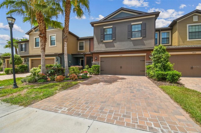 28568 Tranquil Lake Cir, Wesley Chapel, FL 33543 - view of property featuring stucco siding, a garage, and decorative driveway
