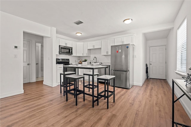 1743 Fulton Ave, Clearwater, FL 33755 - kitchen featuring appliances with stainless steel finishes, white cabinets, light wood-type flooring, and light countertops