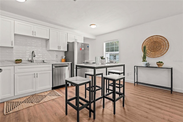 1743 Fulton Ave, Clearwater, FL 33755 - kitchen with appliances with stainless steel finishes, light wood finished floors, backsplash, and white cabinetry