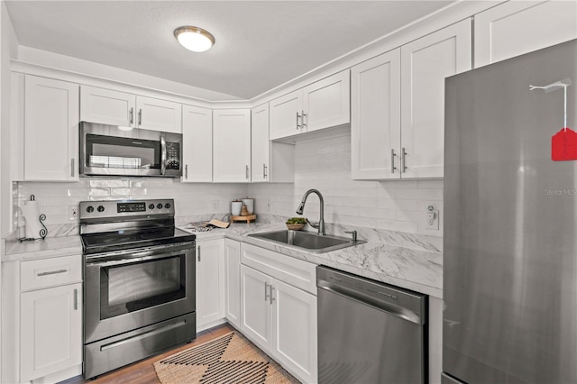 1743 Fulton Ave, Clearwater, FL 33755 - kitchen featuring appliances with stainless steel finishes, white cabinetry, backsplash, and light wood-type flooring