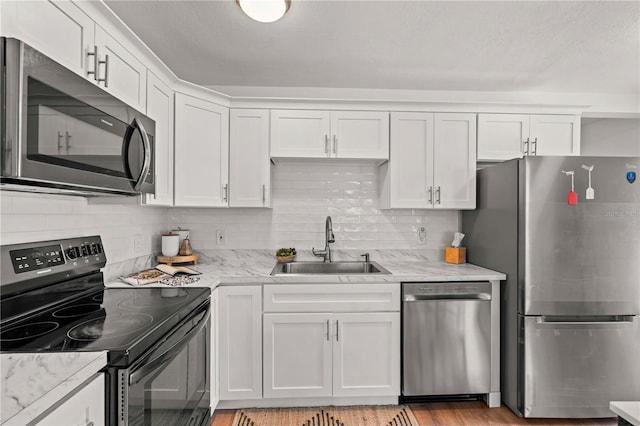 1743 Fulton Ave, Clearwater, FL 33755 - kitchen featuring stainless steel appliances, white cabinetry, tasteful backsplash, light stone countertops, and light wood-type flooring