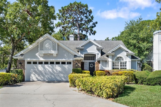 2182 Trevor Rd, Palm Harbor, FL 34683 - view of front of house featuring an attached garage, driveway, brick siding, roof with shingles, and a chimney
