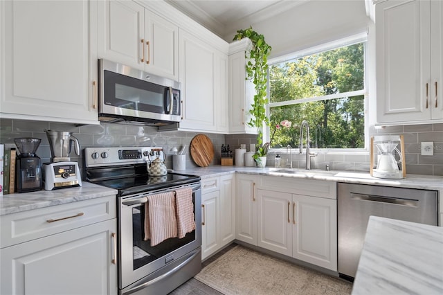 2182 Trevor Rd, Palm Harbor, FL 34683 - kitchen featuring stainless steel appliances, crown molding, white cabinetry, tasteful backsplash, and light stone countertops