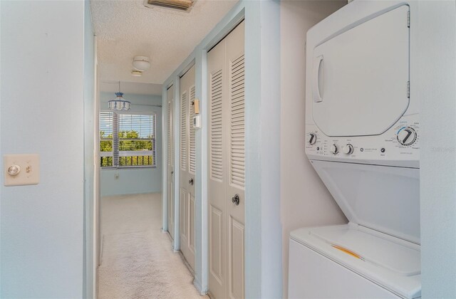 635 30th Ave W Unit F309, Bradenton, FL 34205 - laundry area featuring estacked washer and dryer, a textured ceiling, and light carpet
